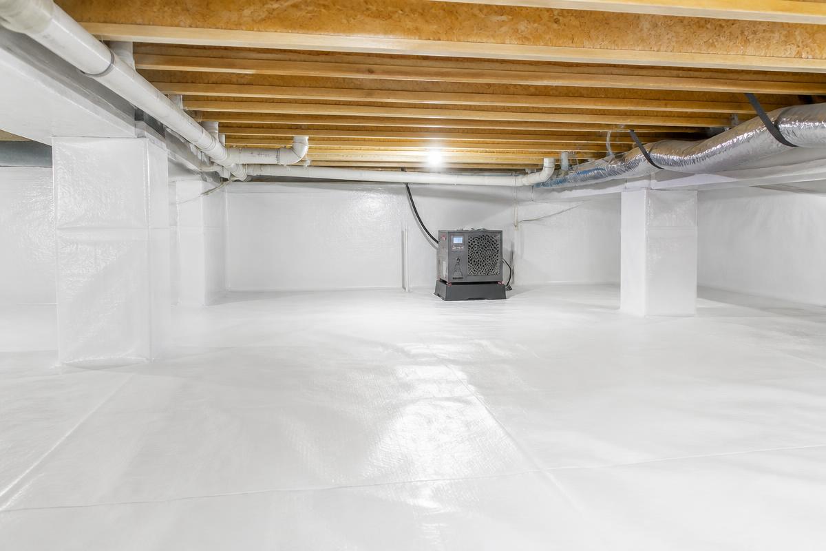Clean, fully encapsulated crawl space with white vapor barrier and dehumidifier after encapsulation